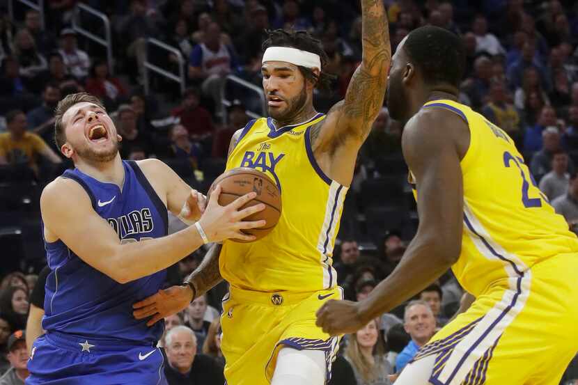 Dallas Mavericks forward Luka Doncic, left, is fouled by Golden State Warriors center Willie...