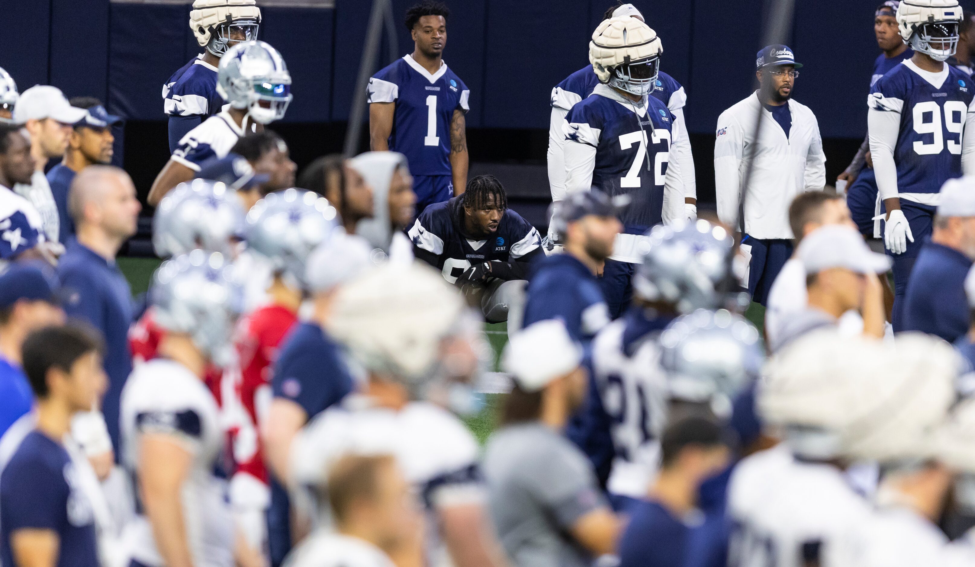 Dallas Cowboys defensive end Tarell Basham, kneeling, looks on from the sidelines after...