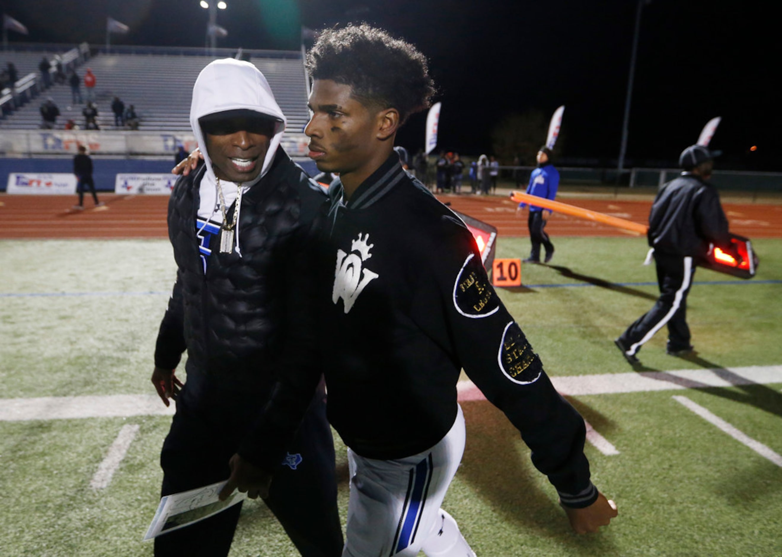 Trinity Christian's offensive coordinator Deion Sanders talks to his son and quarterback...