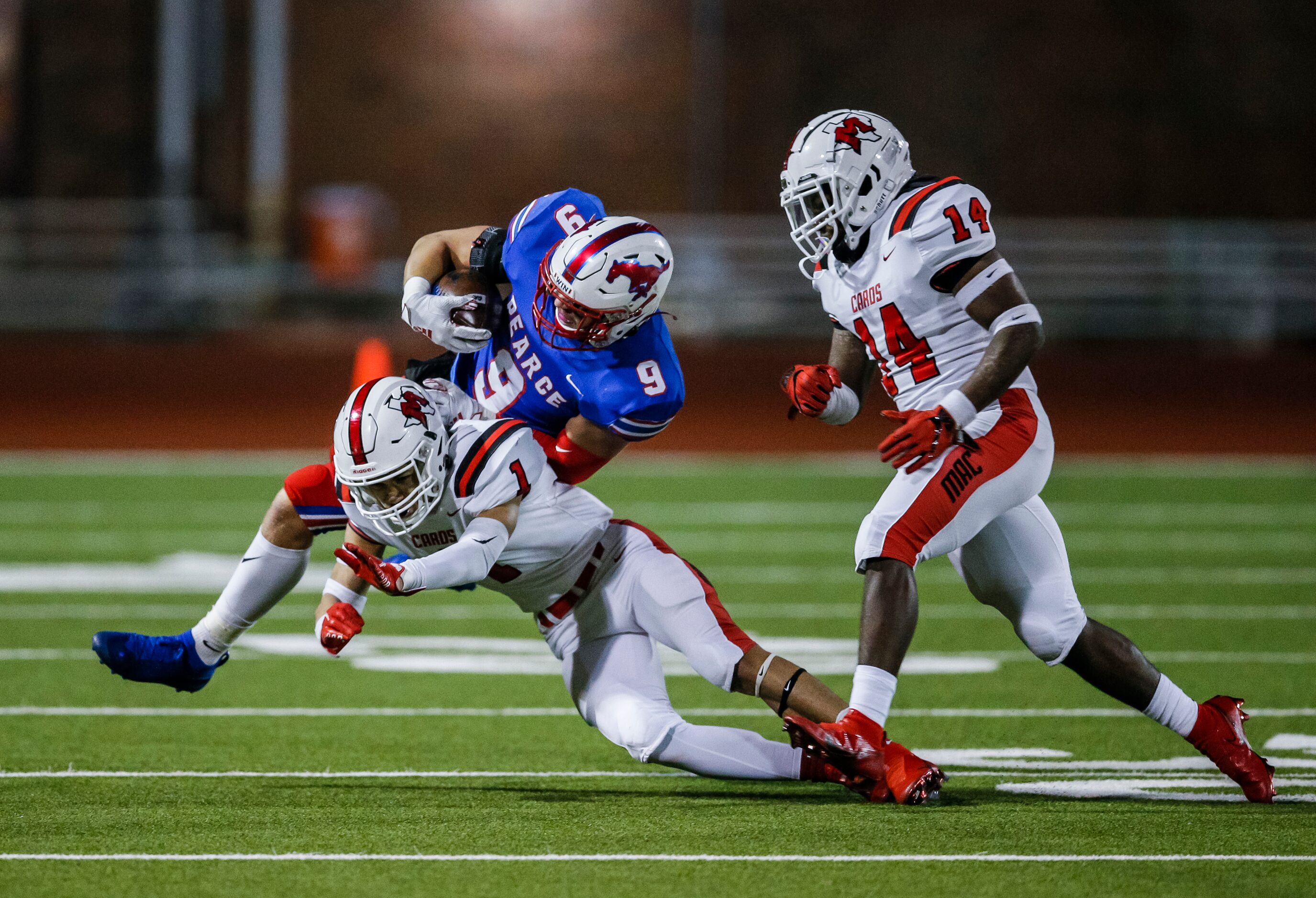 Irving MacArthur seniors Roland Jackson (1) and Chandler Neal (14) tackle JJ Pearce senior...