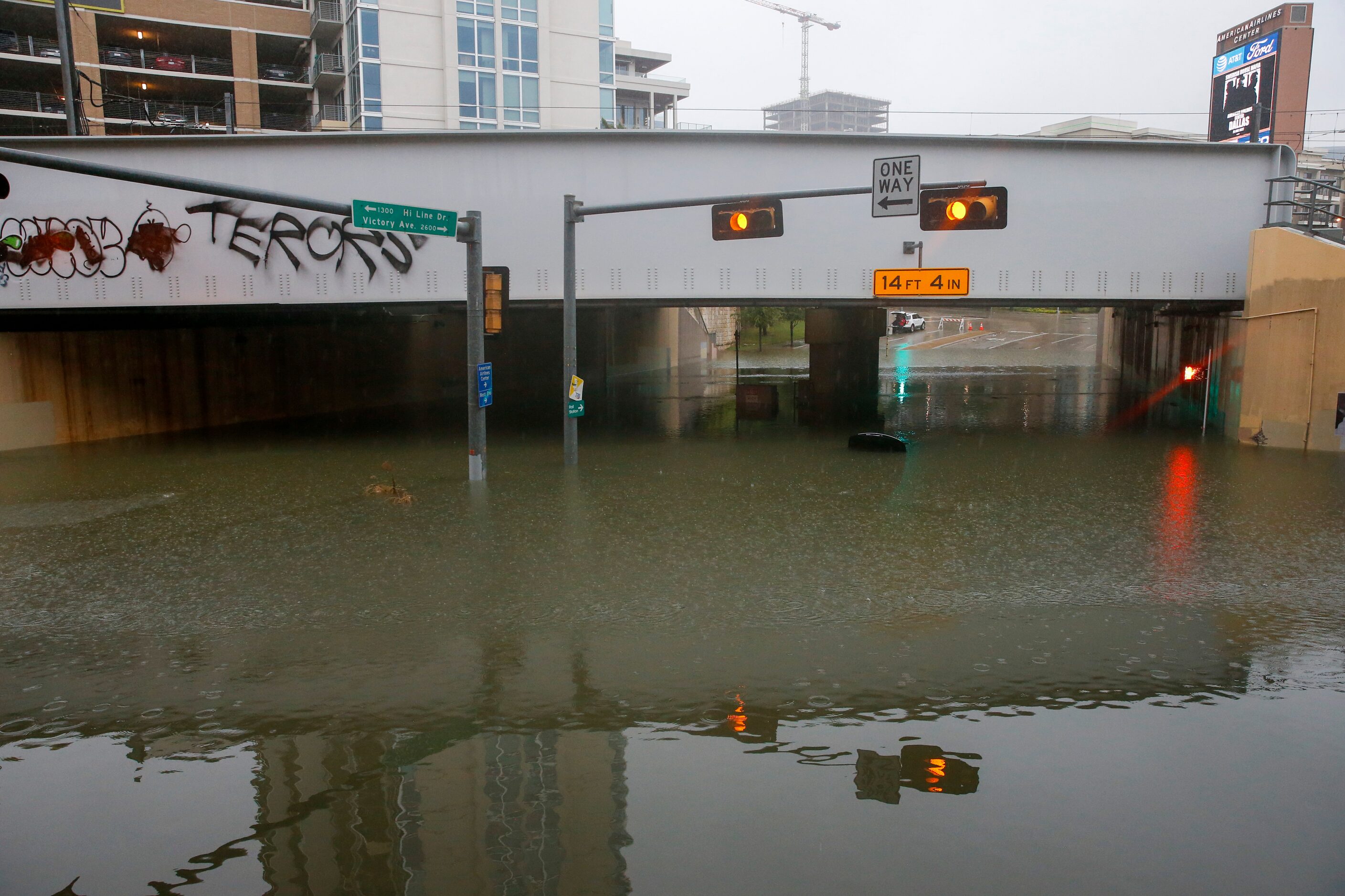 A car with only the trunk visible sits abandoned in flood waters at the intersection of...