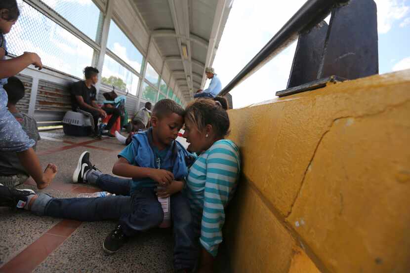 A migrant mother and child share a moment after camping out on the Gateway International...
