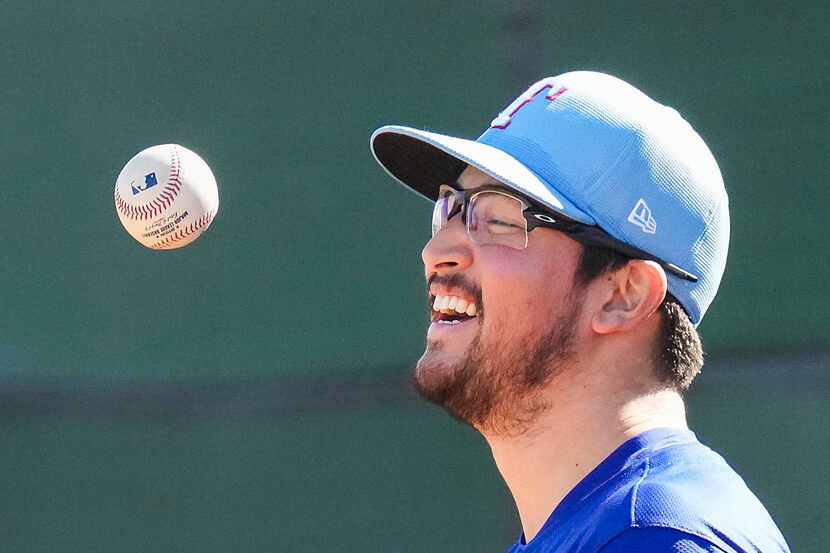 Texas Rangers pitcher Dane Dunning laughs as he tosses a ball before pitching in the bullpen...
