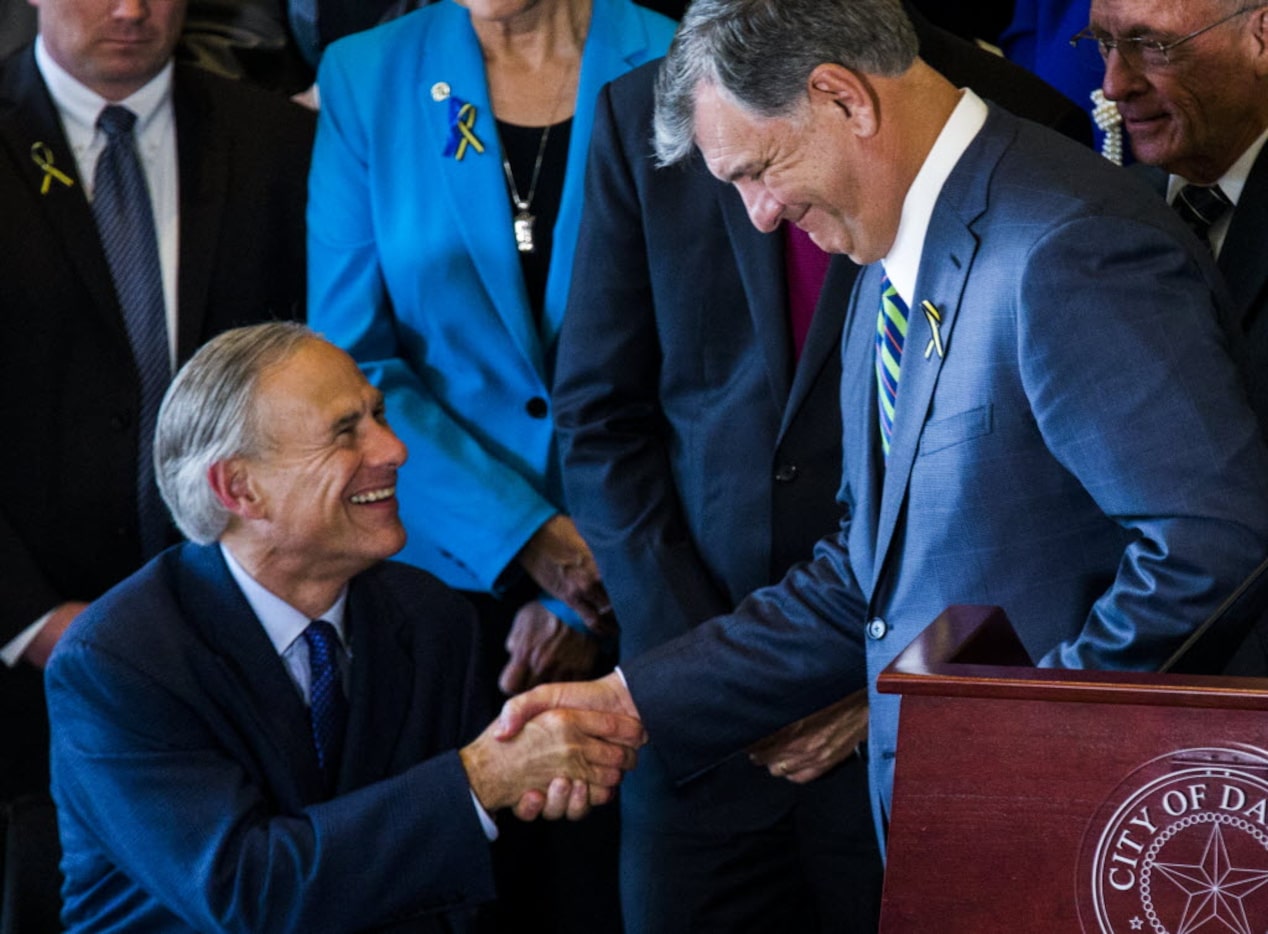 Texas Governor Greg Abbott (front, left) and Dallas Mayor Mike Rawlings (front, right) shake...