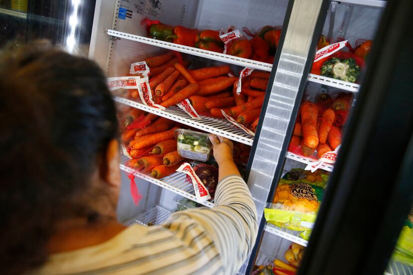 A participant of the food program grabs some vegetables out of the cooler at CitySquare...