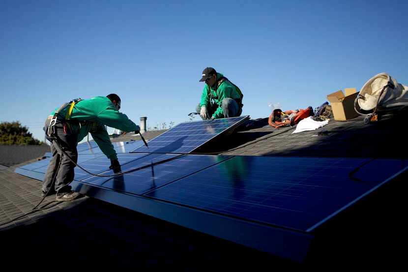 
Solar City workers install solar panels on the roof of a house in San Leandro, Calif. The...