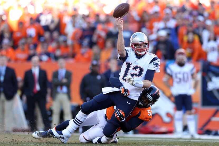 New England Patriots quarterback Tom Brady (12) is brought down by Denver Broncos defensive...