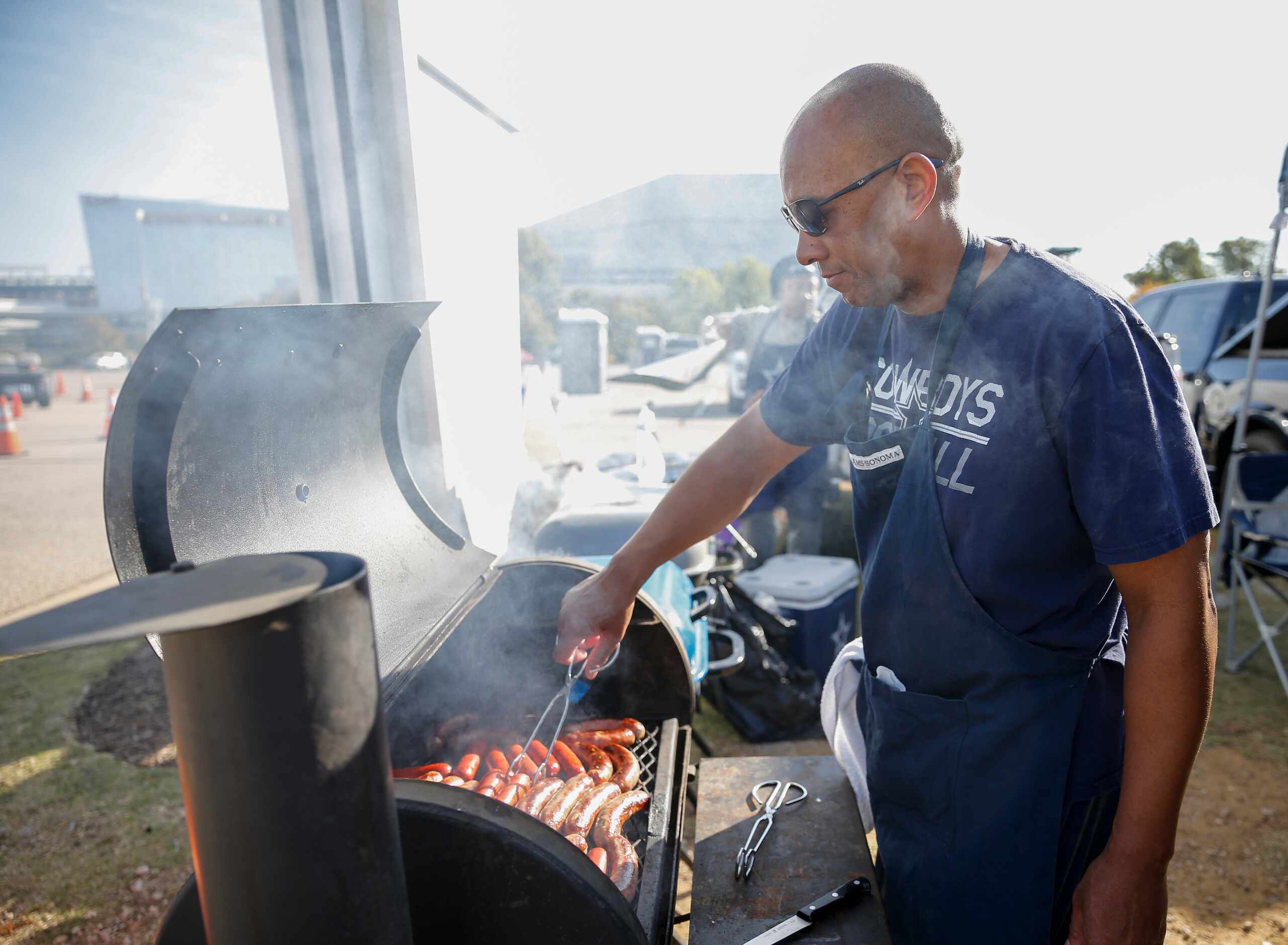 Barry Gaskin, 52, tends to the grill before an NFL football game between the Dallas Cowboys...