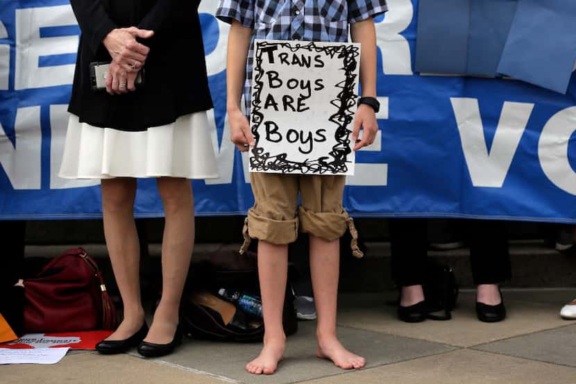 Max Briggle holds a sign as he joins other members of the transgender community during a...