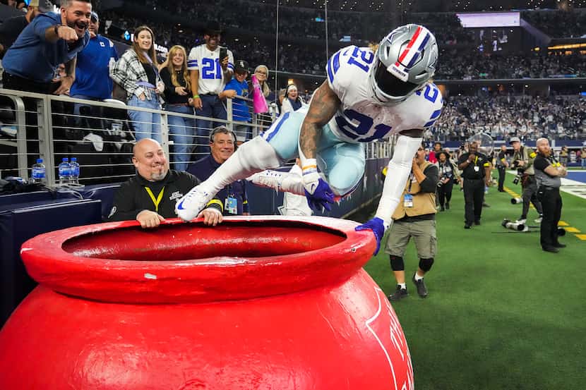 Dallas Cowboys running back Ezekiel Elliott (21) leaps into a Salvation Army kettle in...