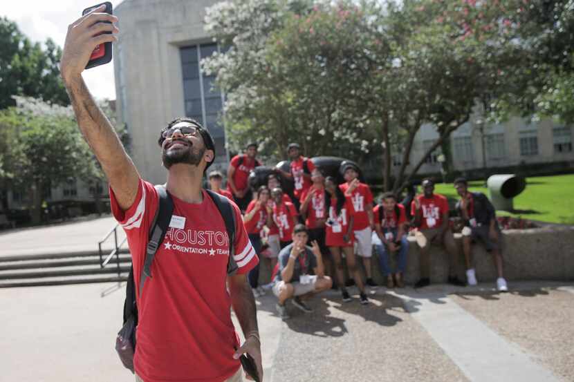 Karim Motani, a junior at the University of Houston, takes a group photo of incoming...