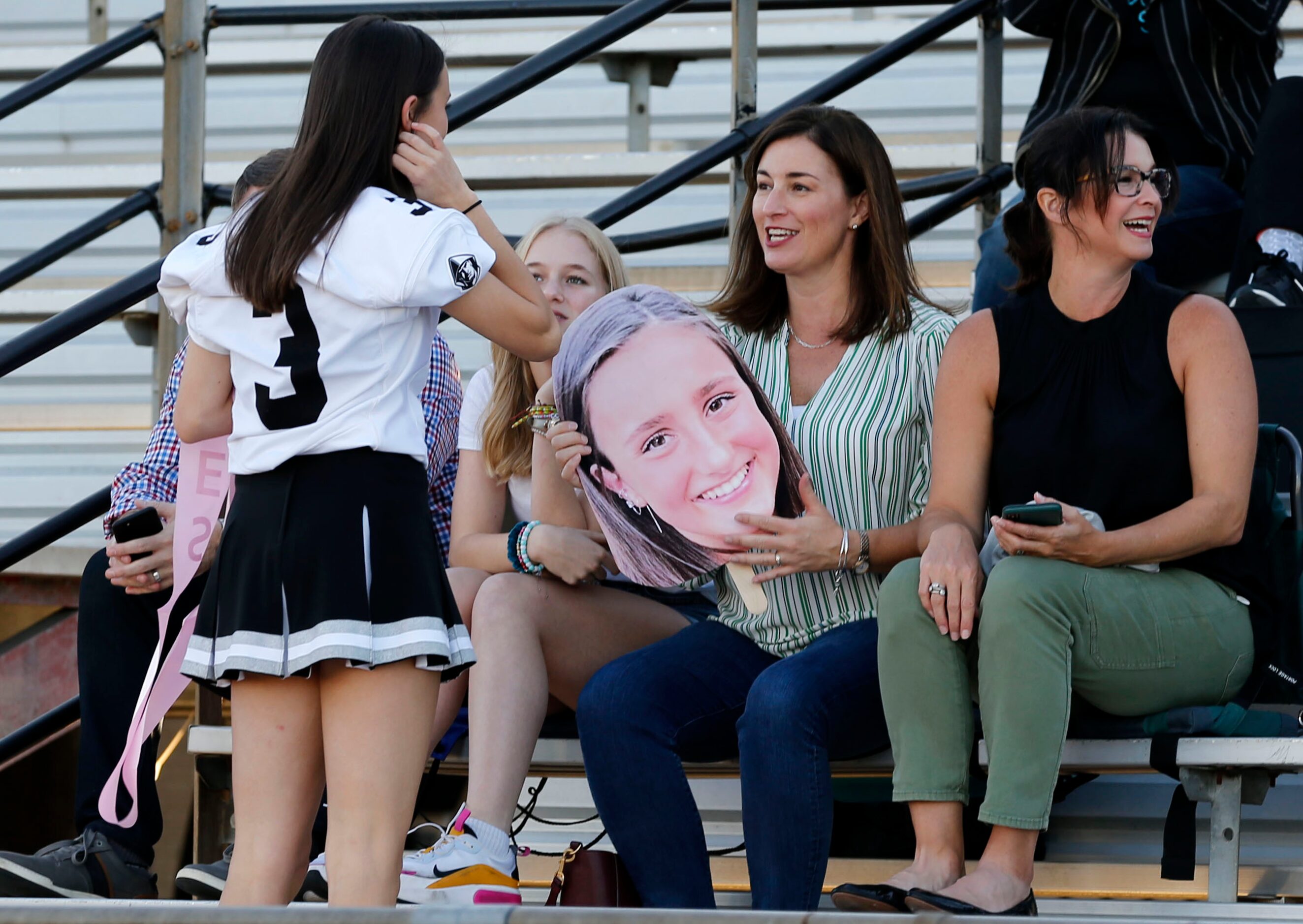 Bishop Lynch senior Kacey Ferguson (3) chats with friend Kate Simpson (holding a big head of...