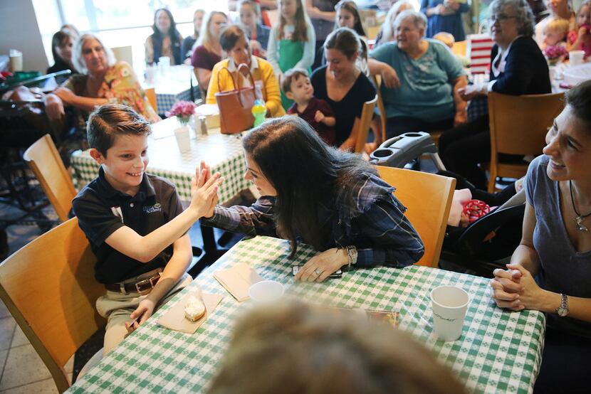 Ashley Grossfeld of Dallas gives a high-five to her son Jonathan Grossfeld, 10, after it was...