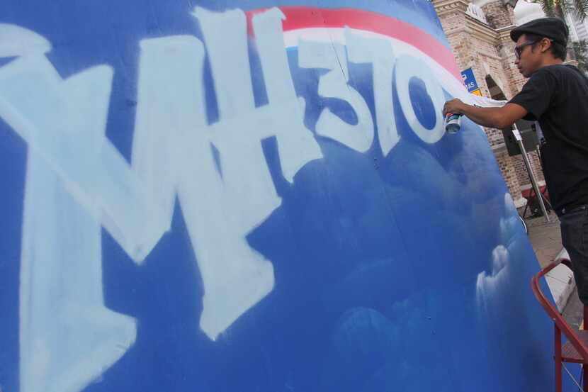 A graffiti artist works on a graffiti featuring the missing Malaysia Airlines Flight MH370...