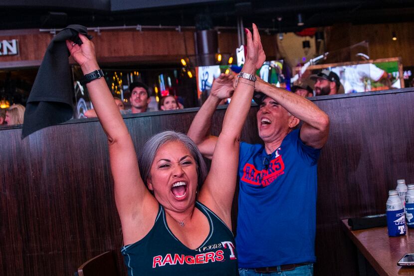 Claudia Borunda (left), from California, cheers with fans as the Texas Rangers win their...