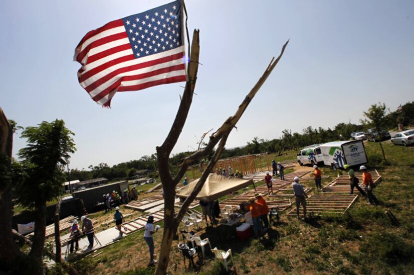 A flag waved from a tornado-damaged tree June 26 as Habitat for Humanity volunteers began a...