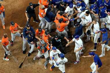 Jugadores de los Astros de Houston y los Rangers de Texas limpian las bancas después de que...