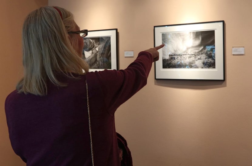 
Sandy Faltermeier of Dallas points at one of Terry Cockerham photographs at the Irving Arts...