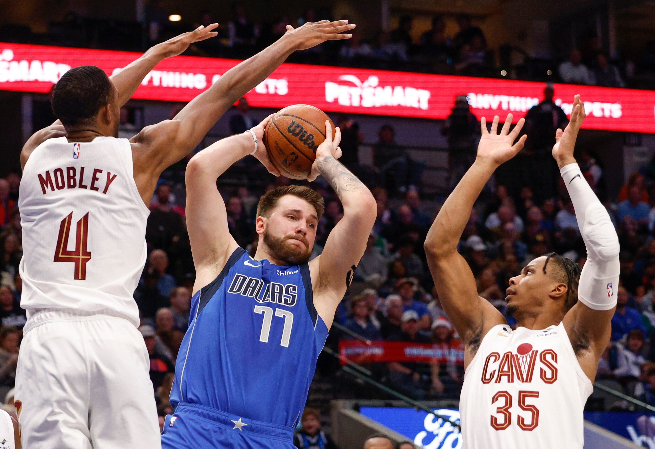 Dallas Mavericks guard Luka Doncic (77) looks to pass the ball between Cleveland Cavaliers...