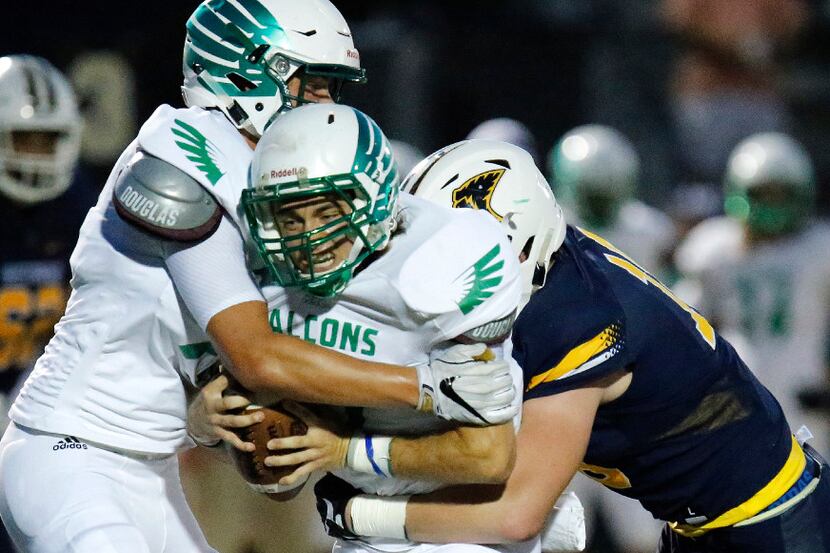 Lake Dallas High School quarterback Spencer Fredericton (7) is caught between his own team...