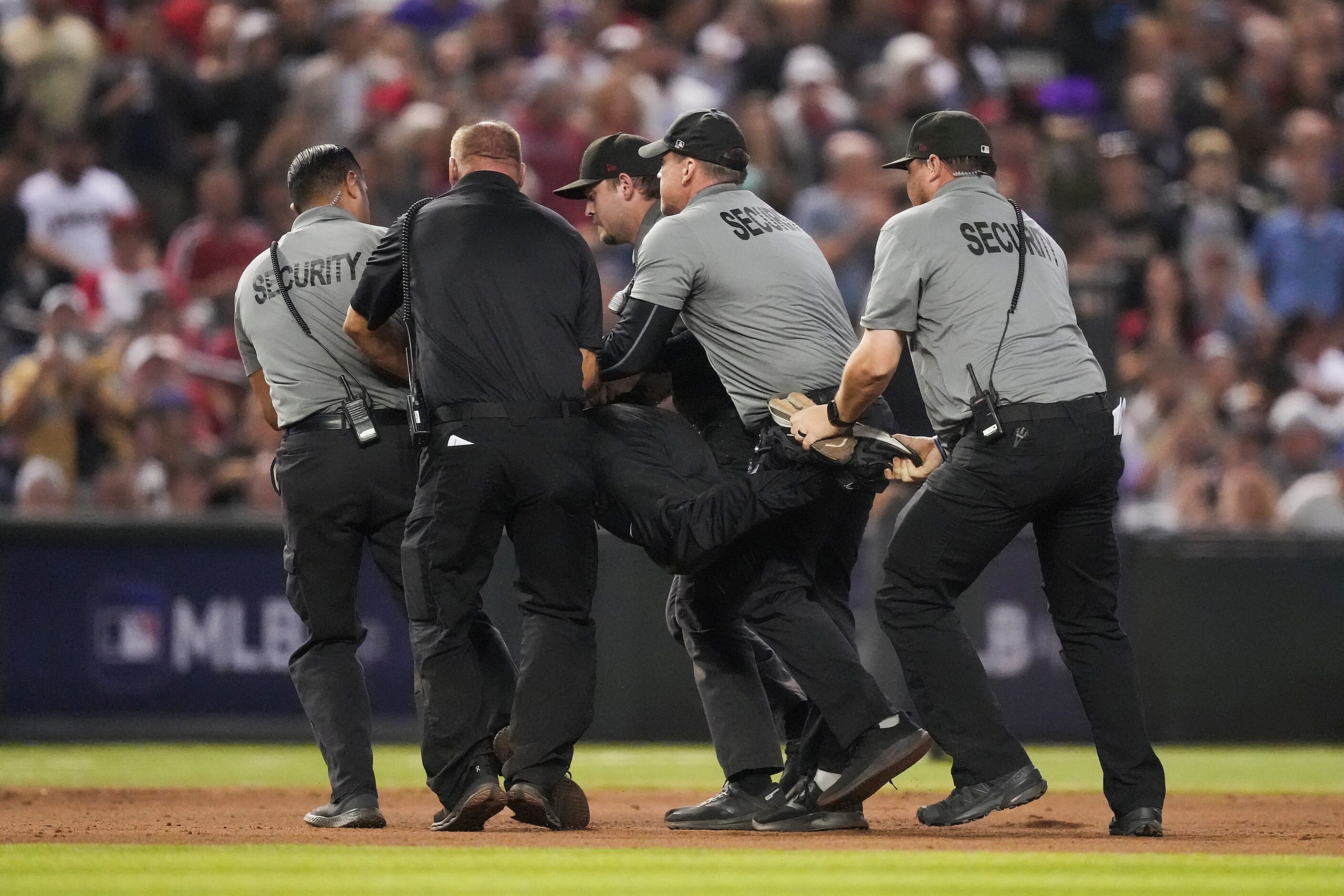 Security carry off a fan who ran onto the field during Game 4 of the World Series between...