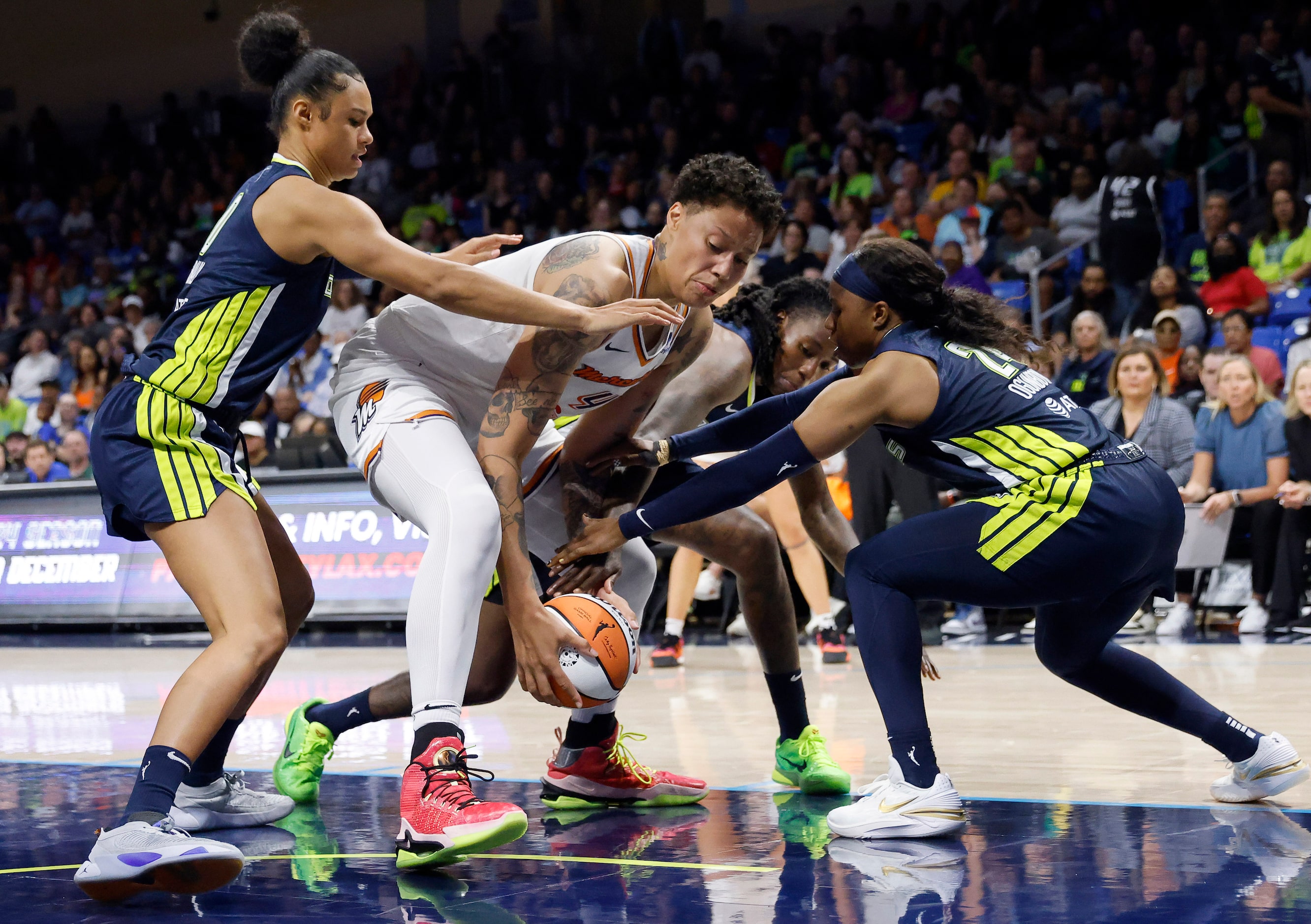 Phoenix Mercury center Brittney Griner (42) fends off Dallas Wings Odyssey Sims (2) and...