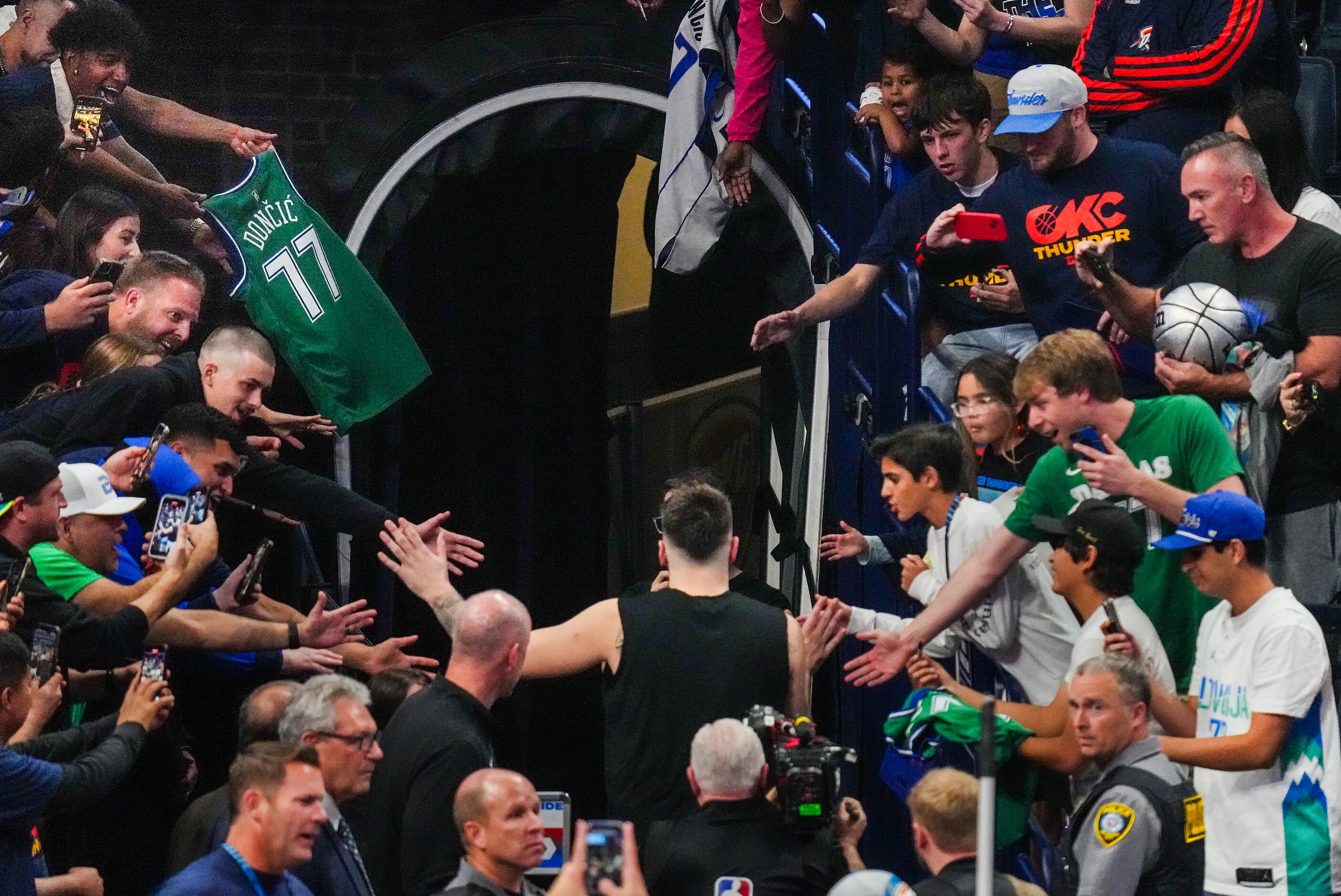 Dallas Mavericks guard Luka Doncic high fives fans as he leaves the court after a victory...