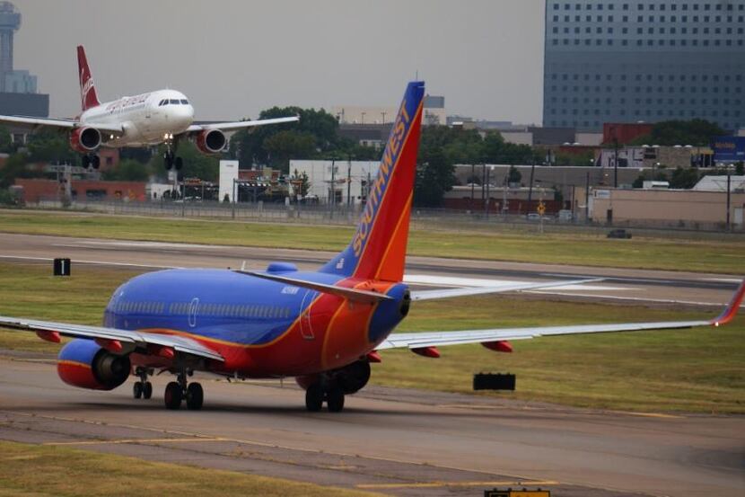  A Virgin America flight arrives at Dallas Love Field as a Southwest Airlines jet taxis...