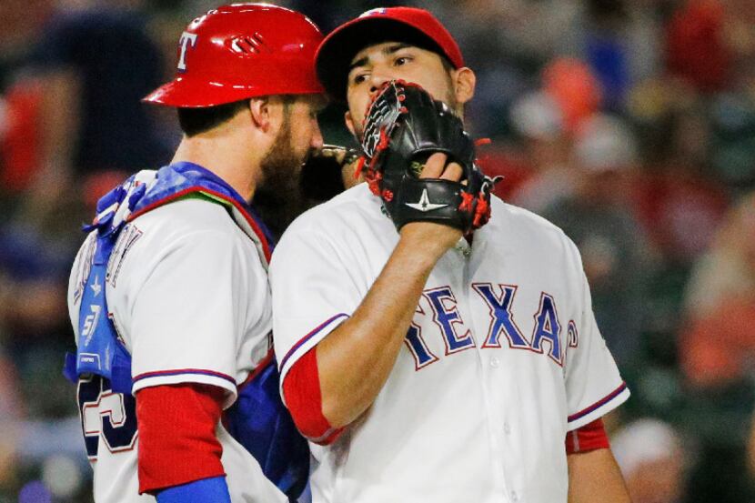 Texas Rangers catcher Jonathan Lucroy (25) and starting pitcher Martin Perez (33) confer in...
