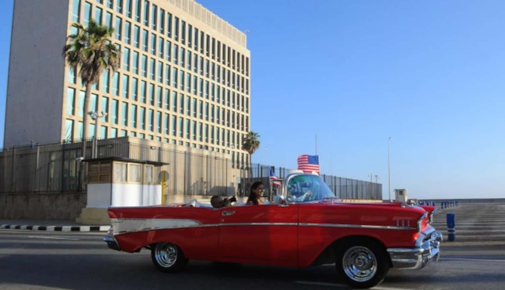 Un carro antiguo pasa al frente de la embajada de Estados Unidos en Cuba. La bandera...