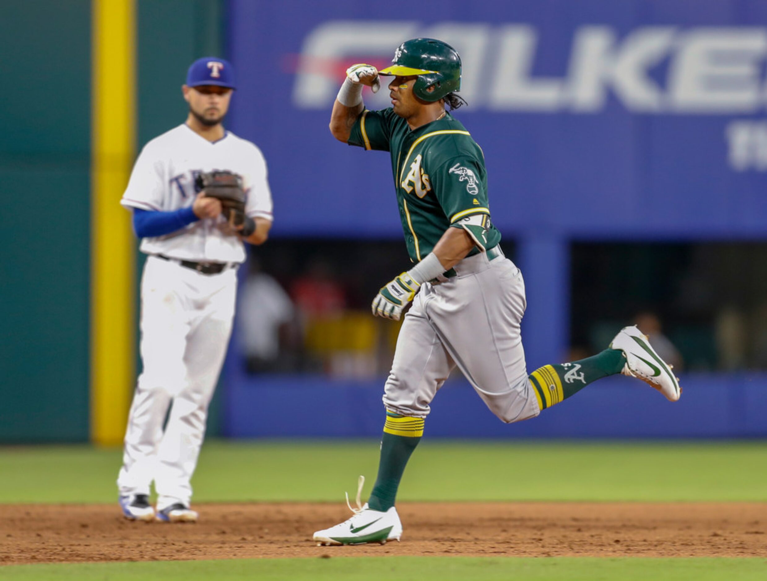 Oakland Athletics' Khris Davis gestures to his team's bench, while passing Texas Rangers...