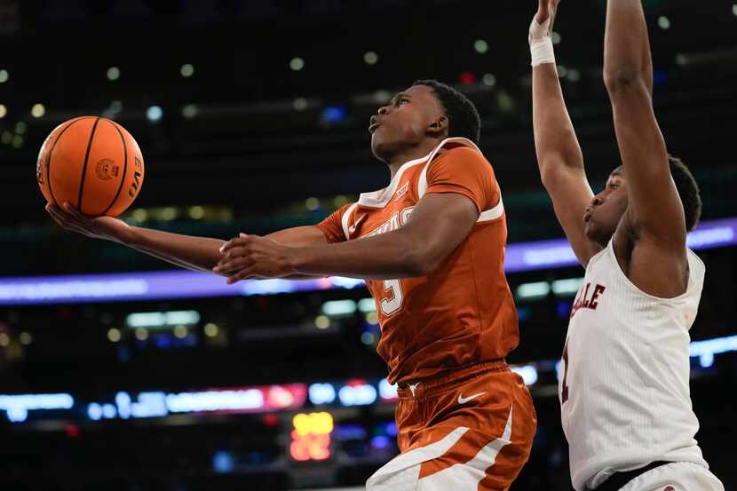Texas's Max Abmas, left, drives to the basket past Louisville's Curtis Williams during the...