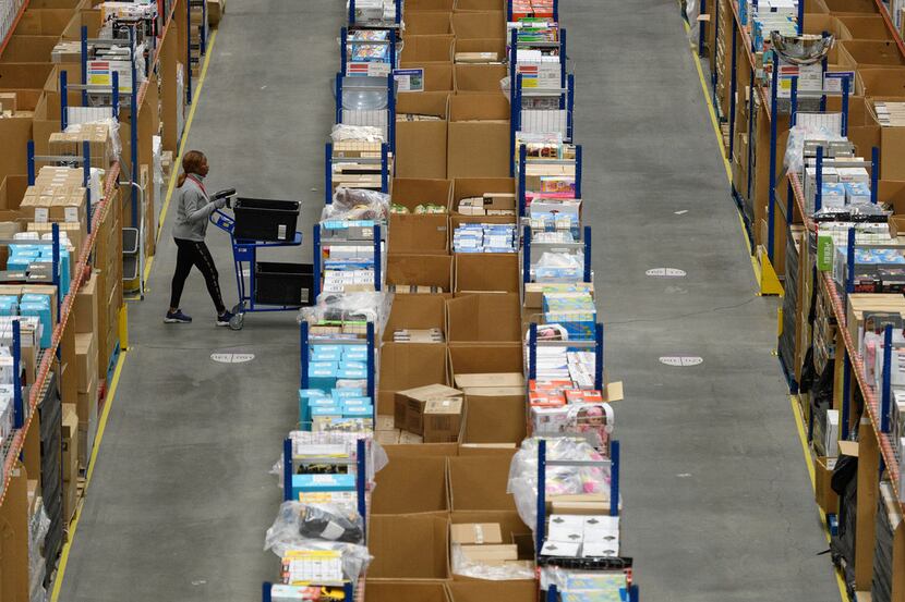 A member of staff picks customer orders from the storage shelves at an Amazon fulfillment...