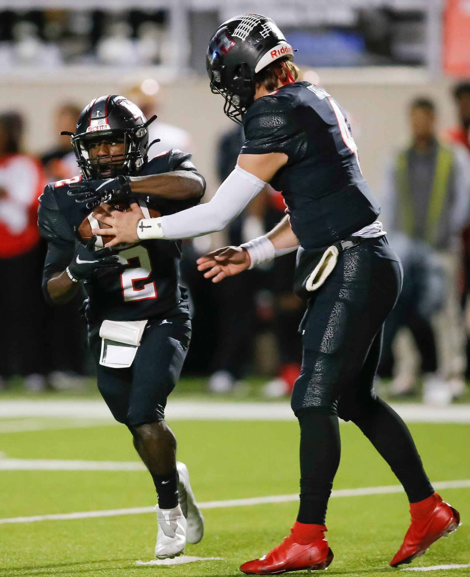 Lake Highlands senior quarterback Caden Dotson, right, hands the ball off to senior running...