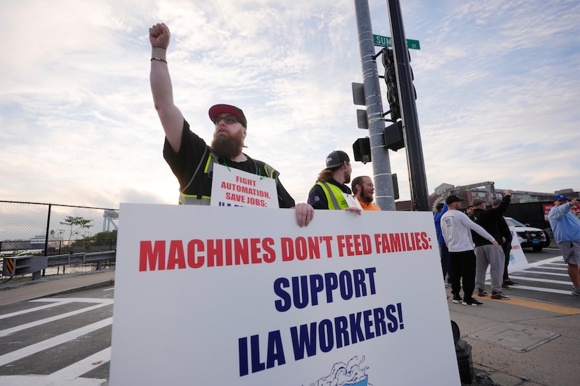 Longshoreman Franky Searle, of Boston, front, displays a placard in front an entrance to a...