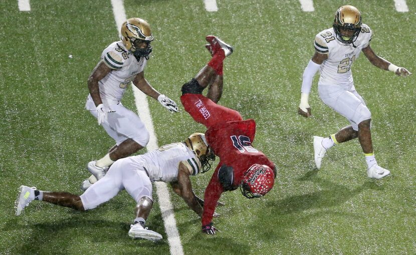 Cedar Hill's Kolbi McGary (31) is flipped after getting tackled by DeSoto's Caleb Abrom (10)...