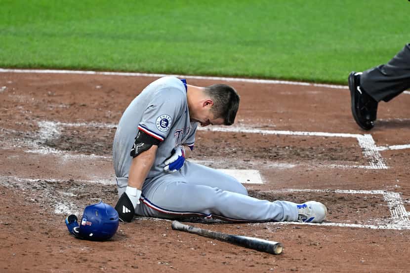 Texas Rangers' Corey Seager sits on the ground after being hit by a pitch thrown by...
