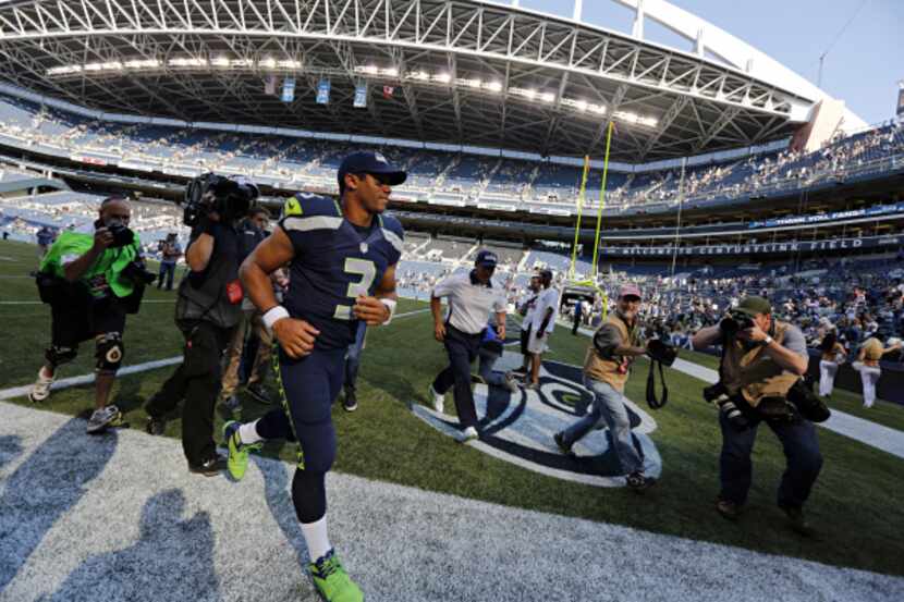 Seattle Seahawks quarterback Russell Wilson is chased by photographers as he leaves the...