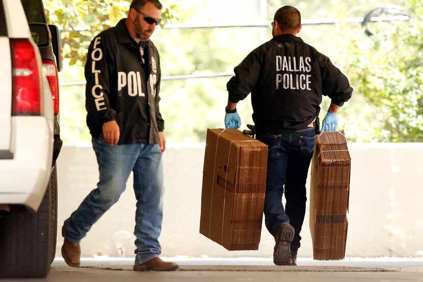 Dallas police officials carry cardboard boxes Wednesday into the Catholic Diocese of Dallas...