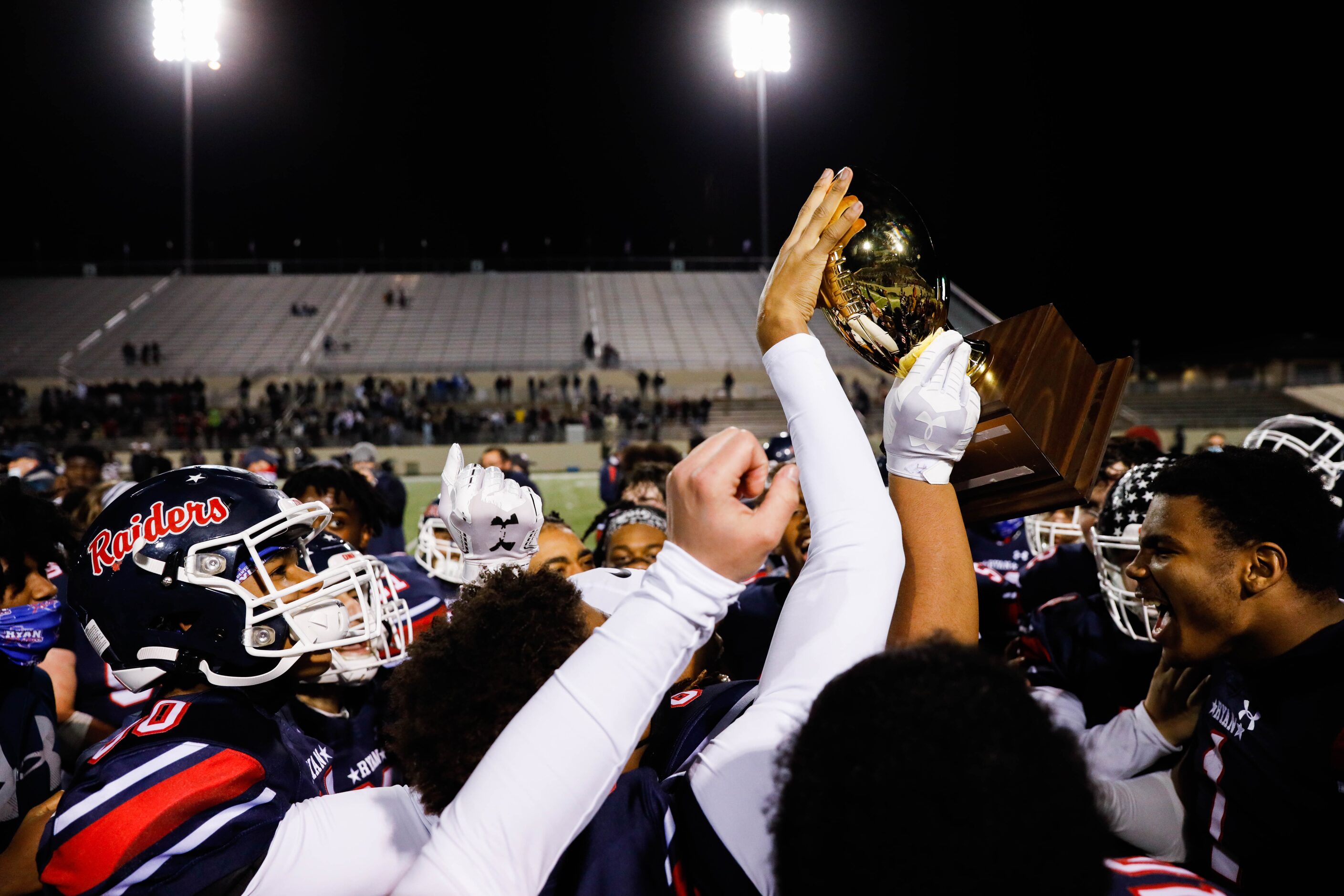 Denton Ryan football players celebrate winning the District 5-5A Division I title against...