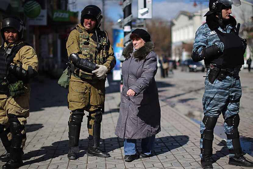 A civilian walks past a line of Russian and Ukrainian Berkut riot police Monday in...