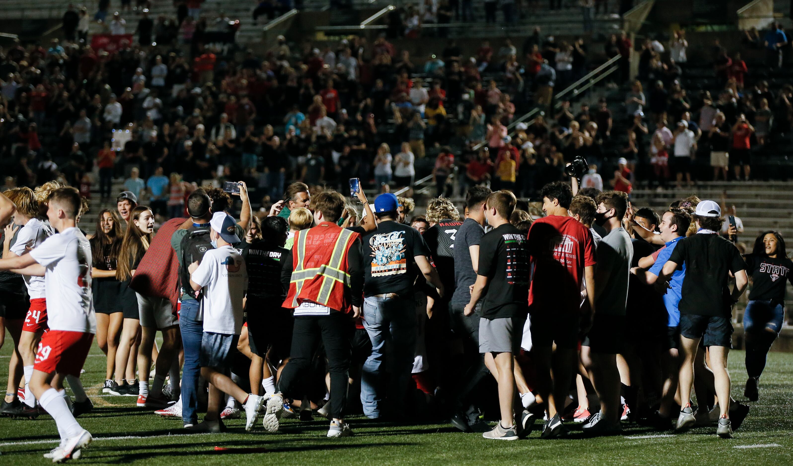 Fans rush the field to celebrate with the Rockwall-Heath boys soccer team after winning the...