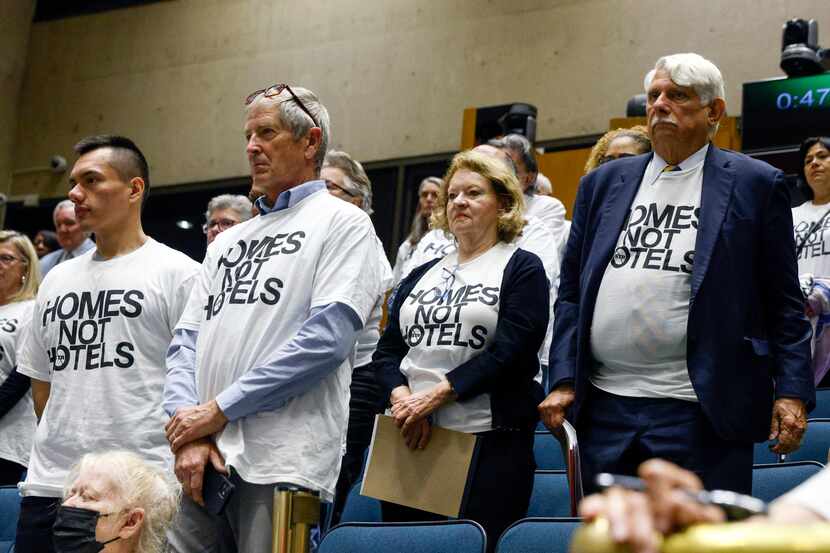 People in opposition to short term rentals stand wearing shirts that read “Homes not Hotels”...