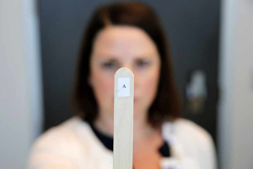 Dr. Erin Reynolds, a neuropsychologist, holds up a tongue depressor with an "A," printed on...