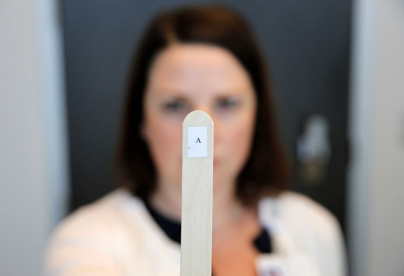 Dr. Erin Reynolds, a neuropsychologist, holds up a tongue depressor with an "A," printed on...