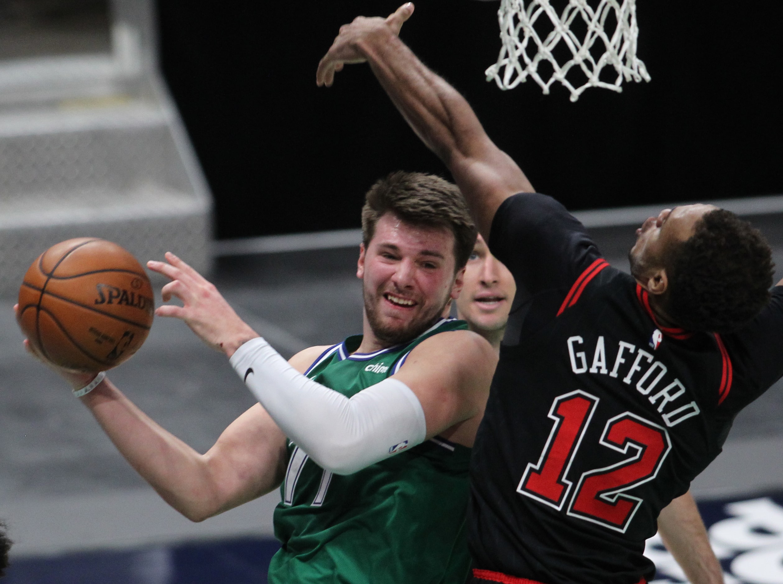 Dallas Mavericks point guard Luka Doncic (77) works under the basket around the defense of...