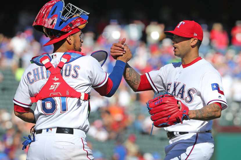 Texas Rangers catcher Robinson Chirinos (61) and relief pitcher Matt Bush (51) shake hands...