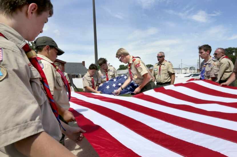  Members of Boy Scout Troop 159 cut the blue field from a retired American flag during a...