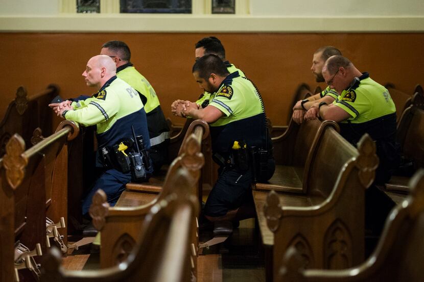 Dallas police officers kneel during a mass in which Father Angel Torres offered a special...