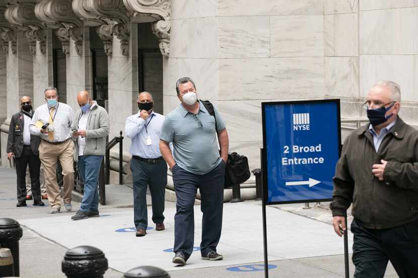 New York Stock Exchange employees wait to enter the building as the trading floor partially...